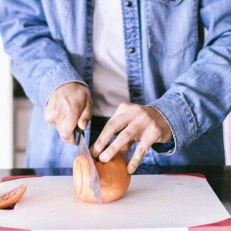 Person cutting tomato on a cutting board