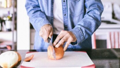 Person cutting tomato on a cutting board