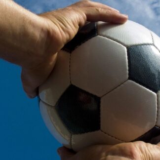 hands holding soccer ball against a blue sky