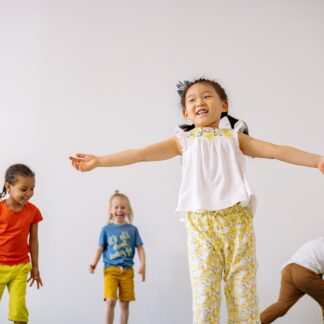 Small children dance and move against a white background.