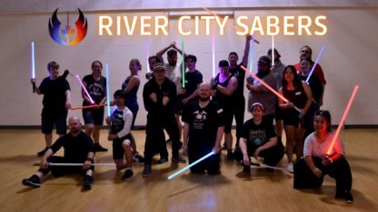 Large group of adults pose with their lightsabers.