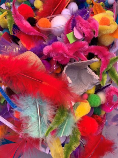 A collection of colourful art supplies including feathers, pipe cleaners, cotton balls among other things.