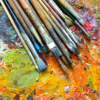 variety of paintbrushes against an abstract painted background.