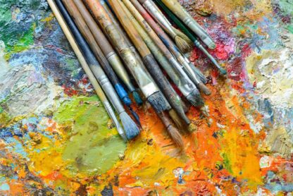 variety of paintbrushes against an abstract painted background.