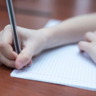 Hand holding a pen writes on a notepad