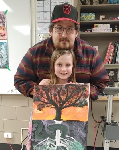 Father and child hold a painting together