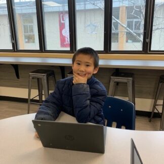 A child looks thoughtful as they work on a laptop