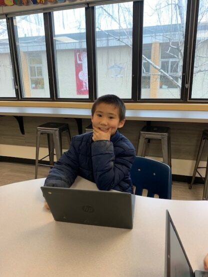 A child looks thoughtful as they work on a laptop