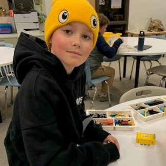 A child looks into the camera while working with Lego