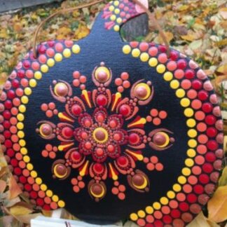 A circular pumpkin cutout is painted with red and yellow dots