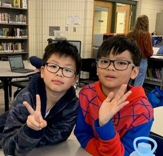 Two children wave at the camera