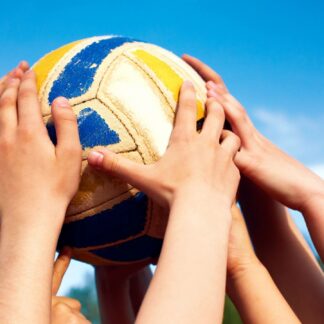 A group of hands collectively holding a volleyball in the air