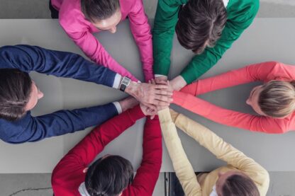 A group of people hold hands in the centre of their circle