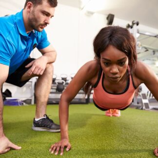 A coach works with a woman doing a pushup