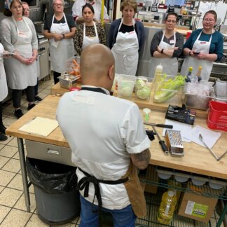 students watch as chef prepares food in a kitchen