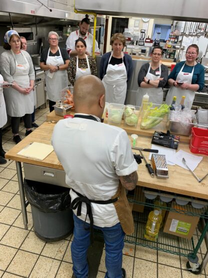 students watch as chef prepares food in a kitchen