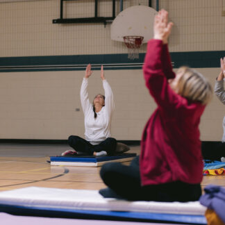 adults sit on mats and reach upwards