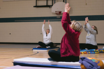 adults sit on mats and reach upwards