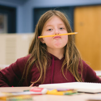 child balances pencil under nose