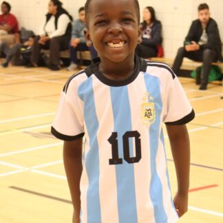 Boy in soccer shirt smiles for camera