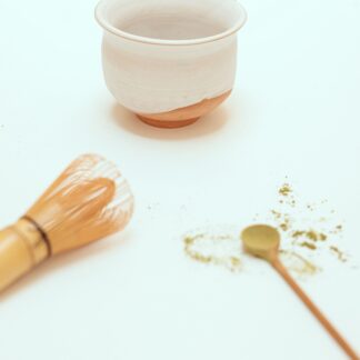 matcha bowl, whisk, and spoon with matcha powder.